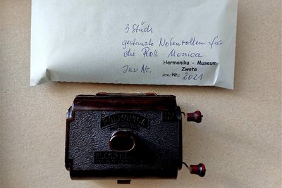 Eine Rollmonica in Bakelit-Gehäuse. Gespielt wird das Instrument mittels einer Mundharmonika und gestanzten Notenrollen, die per Kurbel bewegt werden.