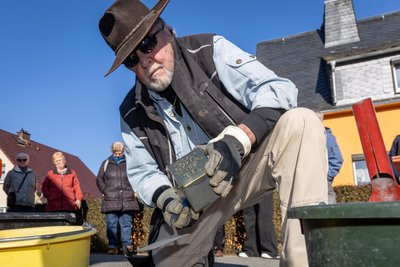 Der Künstler Gunter Demnig setzt in Neukirchen einen Stolperstein in den Gehweg. Mit Kelle und Mörtel befestigt er die Messingtafel, die an Opfer des Nationalsozialismus erinnert.