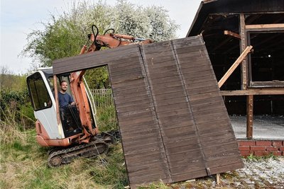 Um den Spielplatz für die Kita zu erweitern, musste eine Gartenparzelle aufgelöst und das frühere Gartenhaus abgebaut werden. Tim Hellert steuert einen Kleinbagger und reißt das Holzhaus auseinander. Foto: Christof Heyden