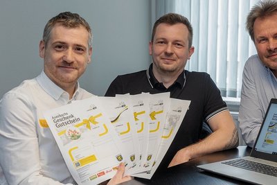 Gestalter Heiko Ebert von HE-Design, Patrick Studinski von HD24 und Citymanager Uwe Prenzel (von links) mit Ausdrucken des neuen digitalen Auerbach-Gutscheins.