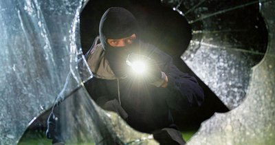 Ein fiktiver Einbrecher blickt an einem Haus durch eine eingeschlagene Fensterscheibe: Die Anzahl der Einbrüche in Wohnungen im Erzgebirgskreis hat sich zuletzt spürbar erhöht. 
