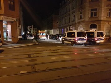 Während ein Verletzter in einem Rettungswagen versorgt wird, nehmen Polizisten die Personalien von möglichen Beteiligten und Zeugen auf. 