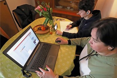 Marina Androsenko bereitet den Unterricht für ihre Schüler vor, während ihr Sohn Maxim Physikunterricht per Smartphone erhält. 