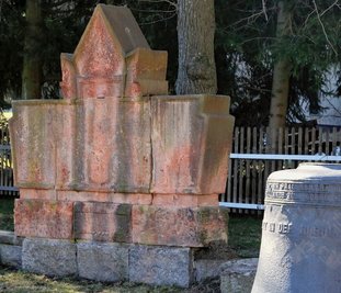 Das Denkmal auf dem Kirchhof in Neuwelt vor dem Abbau. Die Granitsteine bilden auch künftig den Sockel für die behauenen Porphyrblöcke. Der Standort wird beim Wiederaufbau leicht verändert.
