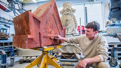 In der Stollberger Steinmetzwerkstatt Scheunert wird das Kriegerdenkmal aus Schwarzenberg-Neuwelt restauriert. Steinmetz und Steinbildhauer Georg Ahner ergänzt unter anderem mehrere Fehlstellen am Krönungselement mit Mörtel. 