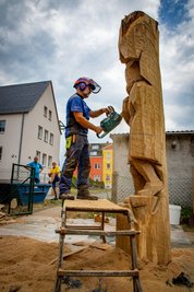 Holzbildhauer Jörg Bäßler sägt aus einem Eichenstamm neben dem Falkenauer Volkshaus einen Bergmann. Der erste Tag sei der schwierigste, sagt Bäßler. Er müsse die Figur im Kopf fertig haben und sozusagen in den Stamm hineindenken und deshalb gut überlegen, bevor er die ersten Schnitte setzt. Es gibt nur drei Markierungen am Holz - für die Position der Füße, des Rumpfes und des Kopfes. Der Rest sei Handwerk, sagt er. 