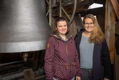 Pfarrerin Rebekka Oesterreich und Kristina Schreckenbach (r.) im Glockenturm der Gelenauer Kirche. Auf der großen Glocken sieht man das Gießjahr 1950.