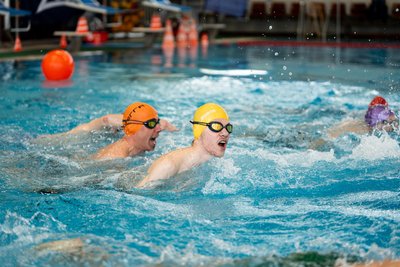Im Schwimmbecken gibt Vater Danny Ehrler (orange Kappe) seinem Sohn Lennard (gelbe Kappe) Kommandos, um die Richtung vorzugeben.