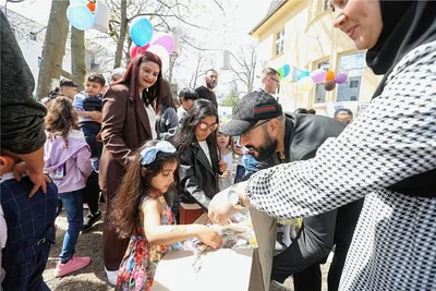 Kinder dürfen sich beim öffentlichen Zuckerfest im Garten des Haus Arthur aus einer Kiste mit Süßgkeiten bedienen. 