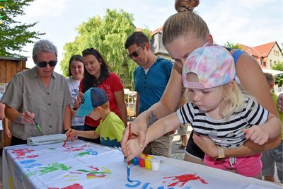 Die zweijährige Fiona (r.) half mit ihrer Mutti, eine farbenfrohes Stoffflies zum Straßenfest in Flöha zu gestalten: Handfläche und Name wurden mit Farbe aufgedruckt.