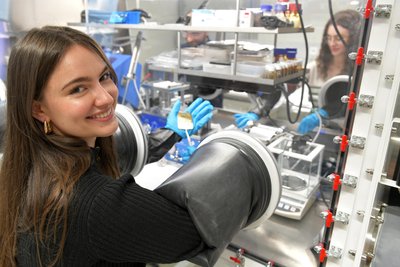 Carolin Herrera demonstriert die Arbeit an einer Handschuhbox. Die Master-Studentin der Angewandten Naturwissenschaften unterstützt ein Forscherteam der TU Bergakademie Freiberg, das eine neuartige Batterie entwickelt hat.