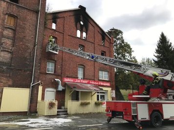 Betroffen von dem Feuer sind ein Fitness-Studio, ein Imbiss und eine Privatwohnung. Verletzt wurde niemand. Der obere Bereich des Giebels wurde inzwischen abgetragen, damit er nicht auf die B 92 stürzt.
