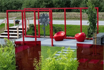 "Farbenspiel":Eine intensive rote Farbe bestimmt den Raum.Gestaltungselemente und Materialien: Pergola, Sitze und drei Glasstelen im Farbkontrast zu weißen Blüten und anthrazitfarbenen Belegen, Sitzplatz als höher gestelltes Deck mit perlgrauen Hohlkammerdielen aus recyceltem Material, keramische Terrassenplatten für die Wege im Farbton schiefer-anthrazit, ein längliches Wasserbecken und die Pergola sind aus pulverbeschichtetem Stahl, an der Pergola sind dünne Drahtseile gespannt, in einem Sternmoos-Teppich wachsen je nach Jahreszeit Tulpen, Margeriten, Sonnenhut, weiße Kletterhortensien für die Pergola und Bambus an den Stelen sowie Zieräpfel im Rasen.Ausführung: Die Gestaltung dauert zwei Wochen. Kosten: 25.000 Euro, aber variierbar. Hersteller: Weigand Landschaft GmbH Oederan
