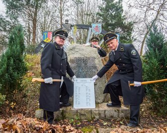 Stefan Schrutek, Andreas Rössel und Rainer Müller (von links) vom Bergbautraditionsverein Wismut haben am Samstag die Tafel am Ehrenhain in Bad Schlema aufgestellt, mit der der im vergangenen Jahr verstorbenen Wismutbergleute gedacht wird. 