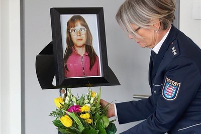 Vor der Pressekonferenz in Jena stellt eine Polizistin Blumen unter das Foto des Mädchens, das 1991 ermordet wurde.