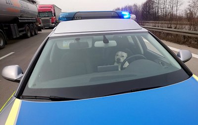 Ein Hund sitzt auf der Autobahn 2 auf dem Fahrersitz eines Polizeiwagens.