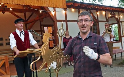 Marco Döbel, der großen Anteil am Wiederaufbau der Bahnwartehalle Rentzschmühle hat, setzte den Gockeschen Hahn zur Krönung aufs Dach des "Kulturbahnhofs". Jörg Gemeinhardt (hinten links) blickte auf den gesamten Prozess von der Idee bis zur Umsetzung des Projekts zurück. 