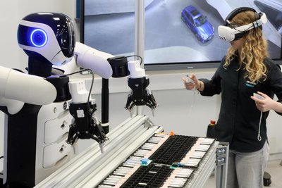 Eine Mitarbeiterin von Hexagon demonstriert, wie der Roboter angelernt wird. Dabei bekommt sie die Perspektive des Roboters im Sichtfeld ihrer VR-Brille angezeigt.