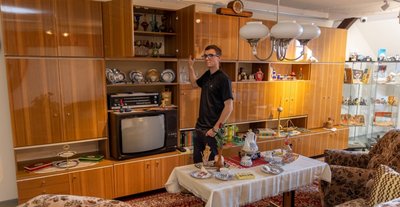 Steve Fiß vor der Schrankwand Carat 2000. Die bietet viel Stauraum und steckt noch voller Schätze aus DDR-Zeiten - vom Kristallglas aus Weißwasser über das Porzellanservice aus Kahla bis zum Berlin-Souvenir. 