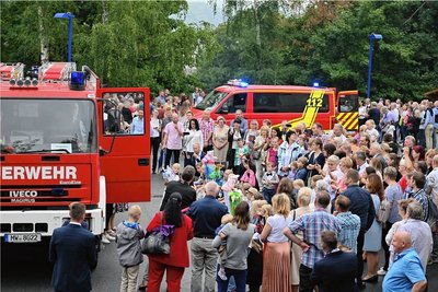 Die Überreichung der Zuckertüten durch Feuerwehrleute, die mit Blaulicht und Sirenen auf den Parkplatz der Regenbogen-Turnhalle fuhren
