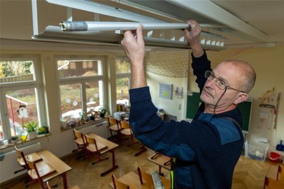 Jens Trommer, Hausmeister und künftiger Energietechniker der Grundschule Steinberg, tauscht in den Klassenzimmern die alten Neonröhren gegen sparsamere LED-Leuchten aus.