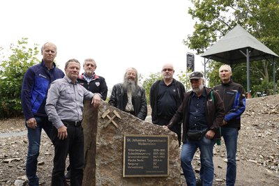 Die Projektverantwortlichen und Mitarbeiter der beauftragten Firmen am Stein mit historischen Daten.