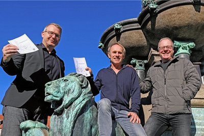 Freibergs OB Sven Krüger verpasst Keimzeit-Frontmann Norbert Leisegang und Kai Suttner, künstlerischer Leiter des Tivoli (v.l.) "Strafzettel" für den verbotenen Ritt auf dem Löwen des Otto-Brunnens. 