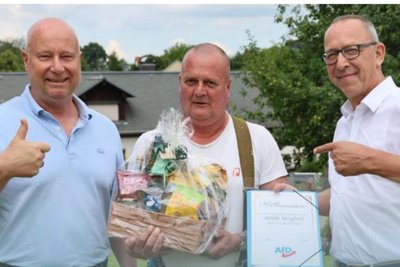 AfD-Generalsekretär Jan Zwerg (links) und Landeschef Jörg Urban (rechts) beim Fototermin im Juli 2025 mit dem 4000. Mitglied, dem Maler Frank Hörnig.