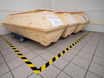           Särge mit der Aufschrift "SARS-CoV-2 positiv - Corona" mit Verstorbenen stehen in der Kühlkammer eines Krematoriums.