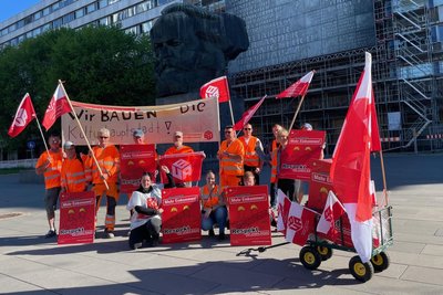 Vor ihrem Umzug durch die Innenstadt haben sich die streikenden Bauarbeiter vor dem Karl-Marx-Monument aufgestellt.