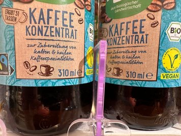 Flaschen mit Kaffeekonzentrat stehen in einem Drogeriemarktregal. (Archivbild)