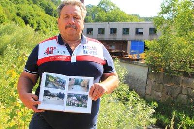 Michael Held mit einem Buch, dass das Hochwasser 2013 auf dem Firmengelände zeigt.