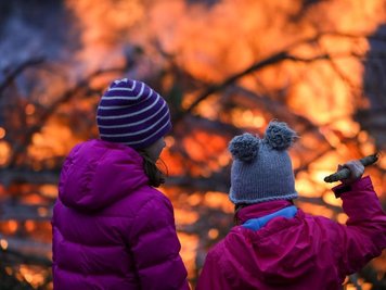             Zwei Mädchen stehen vor einem Osterfeuer.