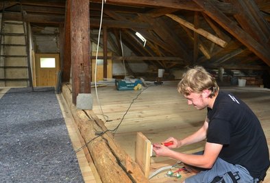 Elektriker Florian Nagel arbeitet derzeit auf dem Dachboden, der bereits für Workshops genutzt werden kann. Viel Holz wurde schon ausgetauscht.