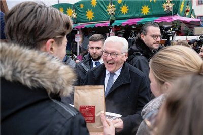 Bundespräsident Frank-Walter Steinmeier bekommt auf dem Weihnachtsmarkt von Schülern Kaffee aus Nepal und einen Kalender geschenkt.