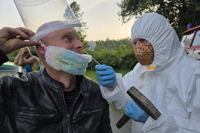 André Haufe aus Markneukirchen (links) und Wolfgang Leupold (rechts) wirken am Film „Maske auf, Genossen“ mit. Hier eine Szene, in der ein Corona-Test auf die Schippe genommen wird - mit einem Hammer und einem Teststäbchen durchgeführt wird. Gedreht wurde am Parkplatz am Krankenhaus in Adorf.