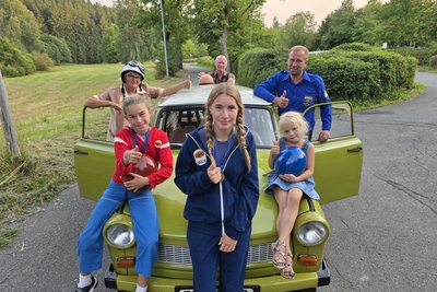 Olivia Geipel (links), Juliana Geipel (Mitte), Amalia Sternitzky (rechts) Marietta Geipel (hinten links), Erhard Geipel (hinten Mitte) und Christian Geipel (hinten rechts) freuen sich, am Film „Maske auf, Genossen“ beteiligt zu sein. Die Familie unterstützt die Filmproduktion mit einen Trabant und zwei Mopeds aus DDR-Zeiten.