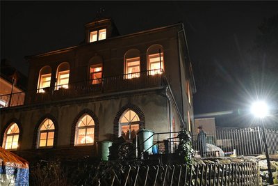 Vom Pfarrhaus geht Licht aus, Schwibbögen sind in die Fenster gestellt.