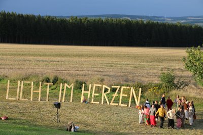 Kreistanz in der Natur neben dem Festival-Motto.
