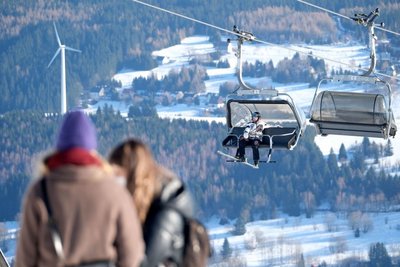 Ein Wintersportler sitzt in der Gondel eines Liftes auf dem Fichtelberg.