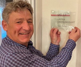 Holger Möckel nimmt nach 30 Jahren Abschied vom Lugauer Ordnungsamt. Die Folie vom Türschild geht mit als Erinnerung mit. Aber auch die Kollegen haben dafür gesorgt, dass er die Zeit mit ihnen nicht vergisst. 