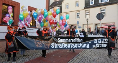 Das Plakat mit dem neuen Termin für den Straßenfasching haben die Frauen und Männer der "Pflasterköppe" am Donnerstagvormittag auf dem Markt entrollt. 