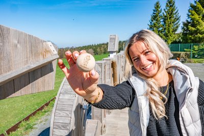 Chefin der Bike- und Skiwelt Schöneck Jennifer Braun. Der neue, hölzerne Schriftzug Schöneck mit der eingebauten Murmelbahn.