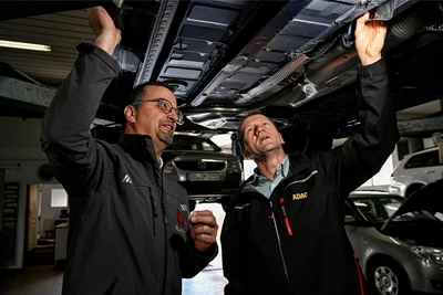 Den Sparmaßnahmen der Autohersteller auf der Spur: ADAC-Techniker Thomas Kubin (r.) und Lackierermeister Jan Dünnebier (l.) beim Begutachten eines Unterbodens.