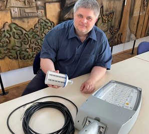 Sascha Wehrmann, Geschäftsführer der Stadtwerke Schwarzenberg, zeigt die neue Technik. In der Hand hält er ein LED-Einschraubmodul und auf dem Tisch liegt ein kompletter Leuchtkopf für Straßenlampen. 