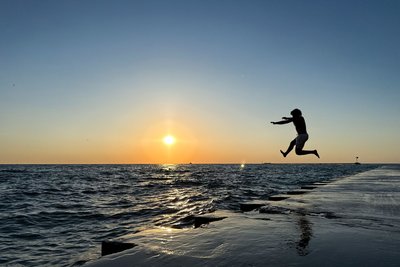 Ein junger Mann springt am frühen Morgen in Chicago von der Promenade am „Oak Street Beach“ in den Lake Michigan.