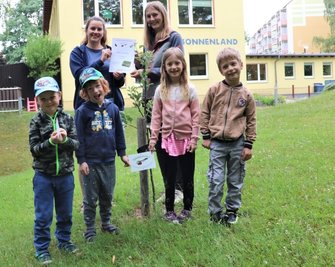 Juliane Seidel (hinten rechts) übergibt an Erzieherin Maria Fischer (hinten links) die Baumpaten-Urkunde. 