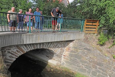 Friedlich fließt der Münzbach normalerweise. Seine Anwohner auf der Brücke wissen jedoch, wie schnell aus ihm ein reißender Strom werden kann.
