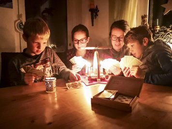 Malte (11), Kira (14), Mutter Katja und Kalle (9) aus Geyer spielen zusammen Karten und machen das Beste aus dem Stromausfall.