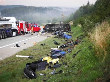             Trümmerteile liegen an der Unfallstelle neben der Autobahn 9, im Hintergrund liegt der umgestürzte Transporter.
